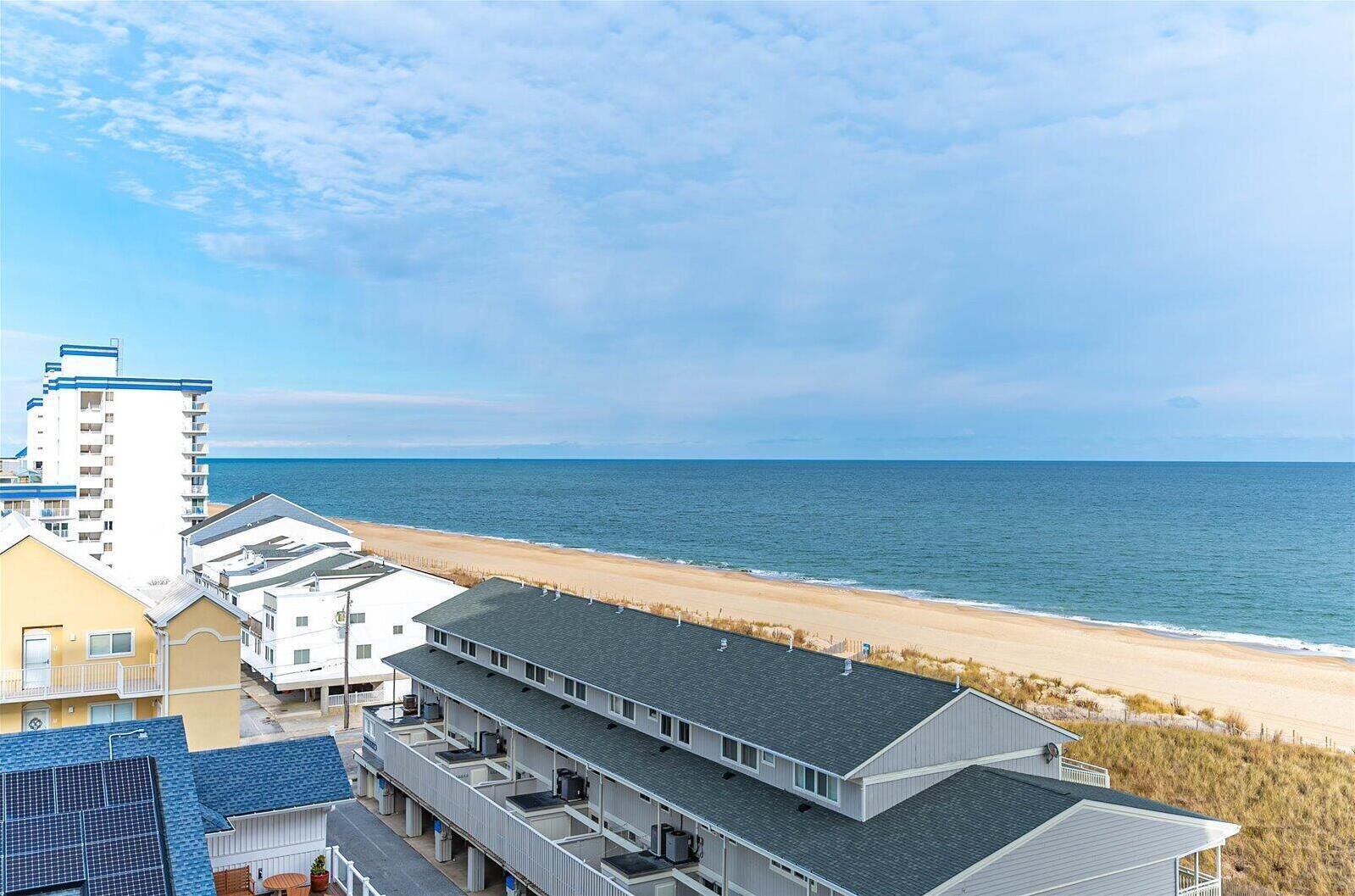 Een hotel aan het strand met meerlaags gebouwen, een zandstrand en de oceaan op de achtergrond.