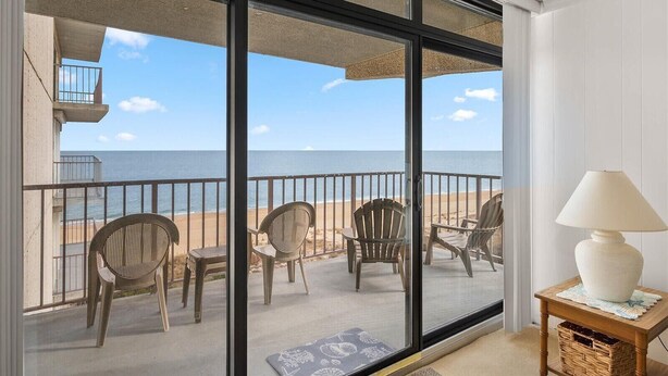 Un balcon avec des chaises et une table, donnant sur une plage.