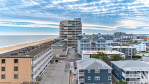 Une ville côtière où se côtoient des bâtiments modernes et traditionnels, dont un grand hôtel imposant et plusieurs propriétés situées en bord de mer.