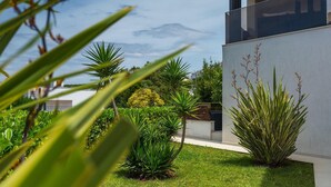 Un edificio moderno con diseño minimalista, rodeado de vegetación cuidada y un cielo despejado.