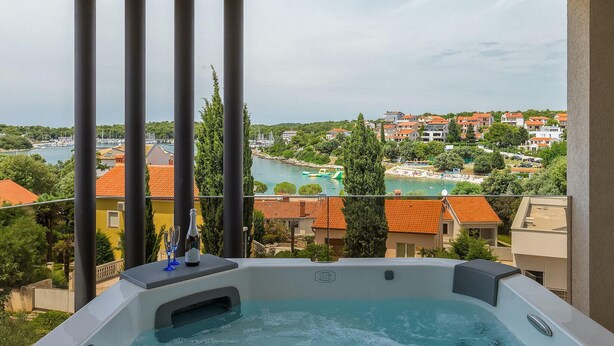 Un jacuzzi con vistas despejadas a un pueblo costero y un puerto deportivo.