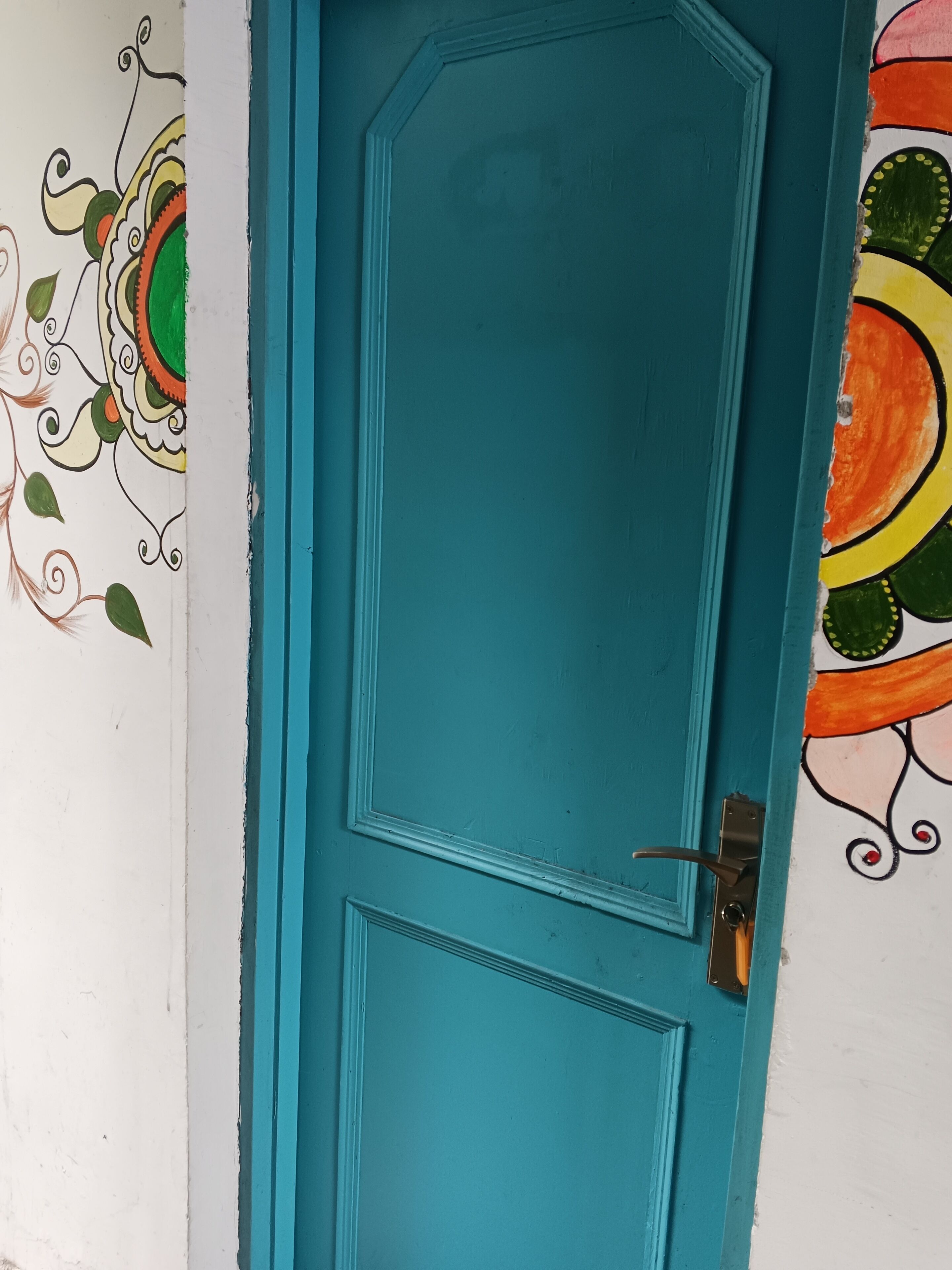 Une porte de couleur bleu-vert avec un design simple, une petite fenêtre et une poignée de porte.
