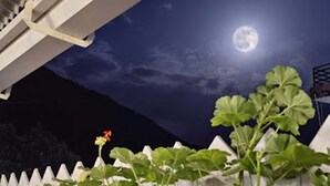 A garden with a white fence, potted plants, and a full moon in the sky. - LA SIESTA INDIA HOSTEL Mcleodganj (Dharamshala)