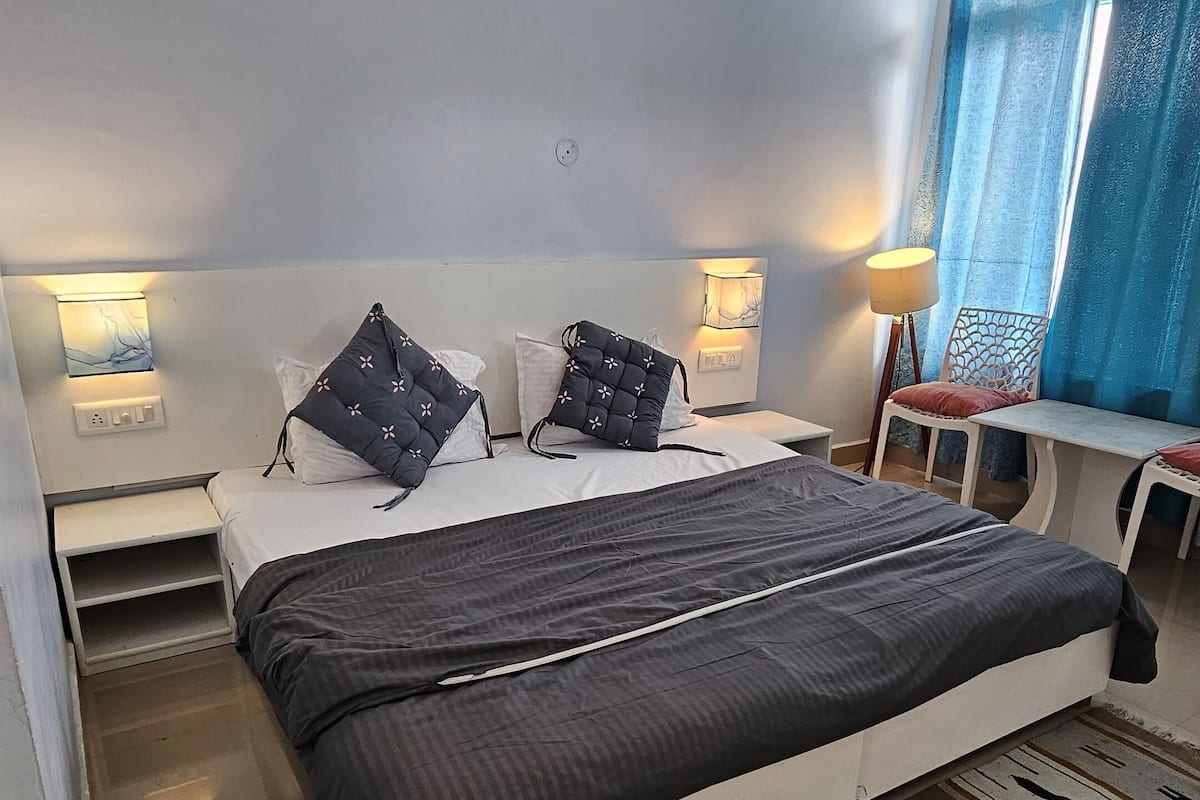 A bedroom with a large bed, bedside tables, a ceiling fan, and a window with curtains.