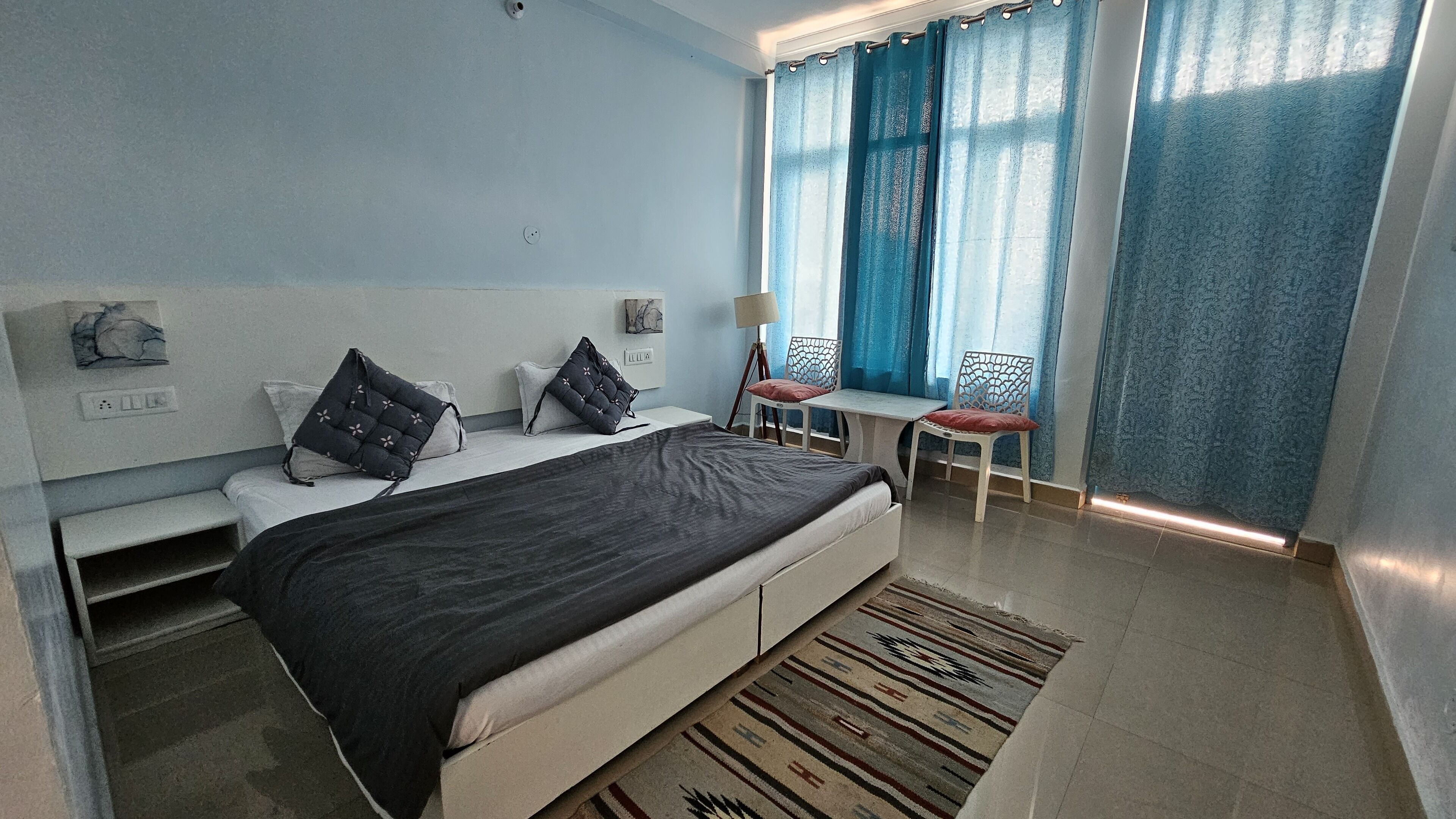 A modern hotel room with a large bed, a desk, and a chair.