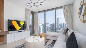 A modern living room with a large window, a flat-screen TV, a round coffee table, and a sofa. - Vogue | 52|42 Marina near Ain Dubai | JBR Beach (Dubai)