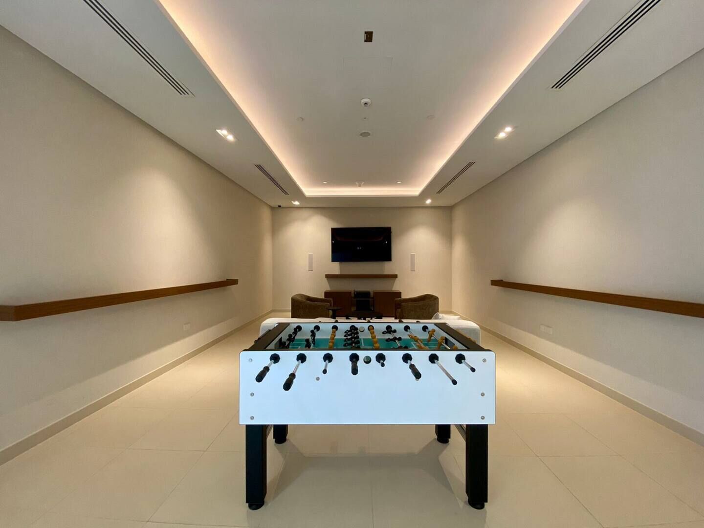 Une chambre moderne équipée d’un baby-foot, d’un téléviseur à écran plat et d’un canapé.