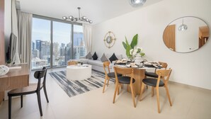 A modern living room with a dining area, large windows, and a city view. - Vogue | 52|42 Marina near Ain Dubai | JBR Beach (Dubai)