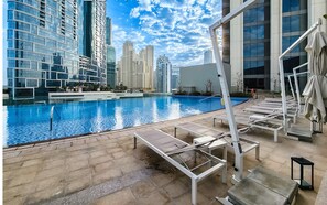 A swimming pool with lounge chairs and a view of high-rise buildings.