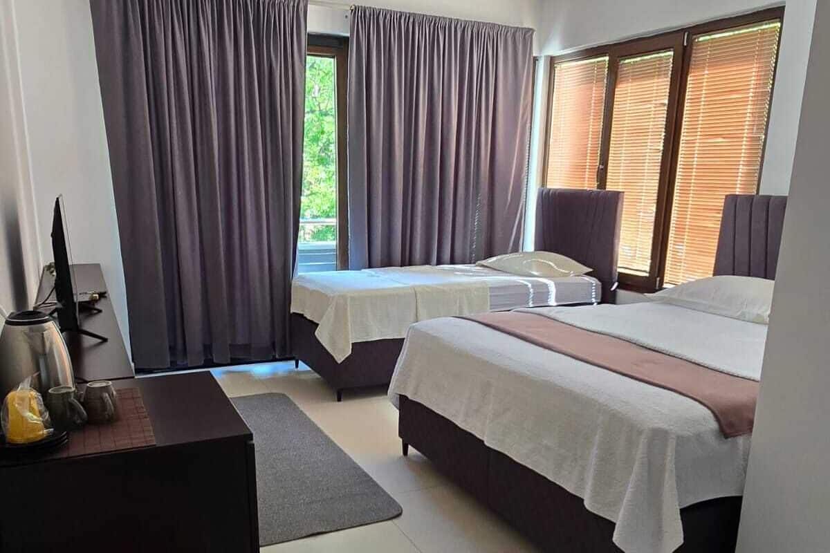 A bedroom with two beds, a desk, and a window with curtains.