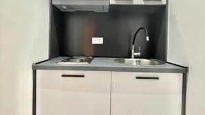 A compact kitchen with a sink, stove, and cabinets. - Apartments TP 777 (Budva)
