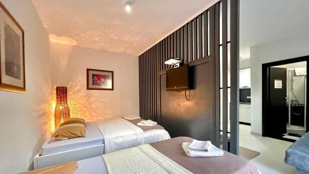 A hotel room with two beds, a TV mounted on the wall, and a modern design. - Apartments TP 777 (Budva)