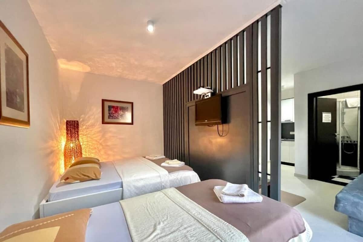 A hotel room with two beds, a TV mounted on the wall, and a modern design.