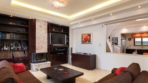 Una sala de estar moderna con chimenea, un televisor de pantalla plana y una estantería.