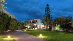 Una casa moderna con piscina, rodeada de césped cuidado y árboles.