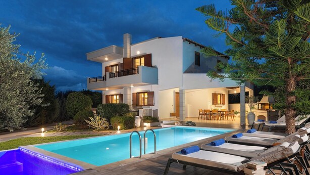 Una casa moderna de dos pisos con piscina, sillas de descanso y zona de comedor.