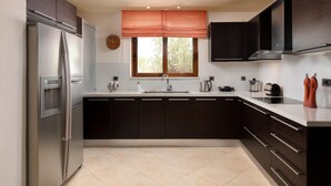 Una cocina moderna con armarios oscuros, un refrigerador de acero inoxidable, una ventana con persianas y un lavamanos.