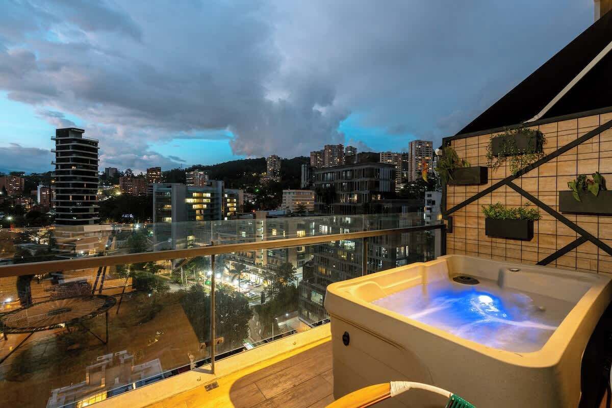 Un balcon doté d’un jacuzzi, offrant une vue sur la ville, et agrémenté d’un mur carrelé avec des jardinières.
