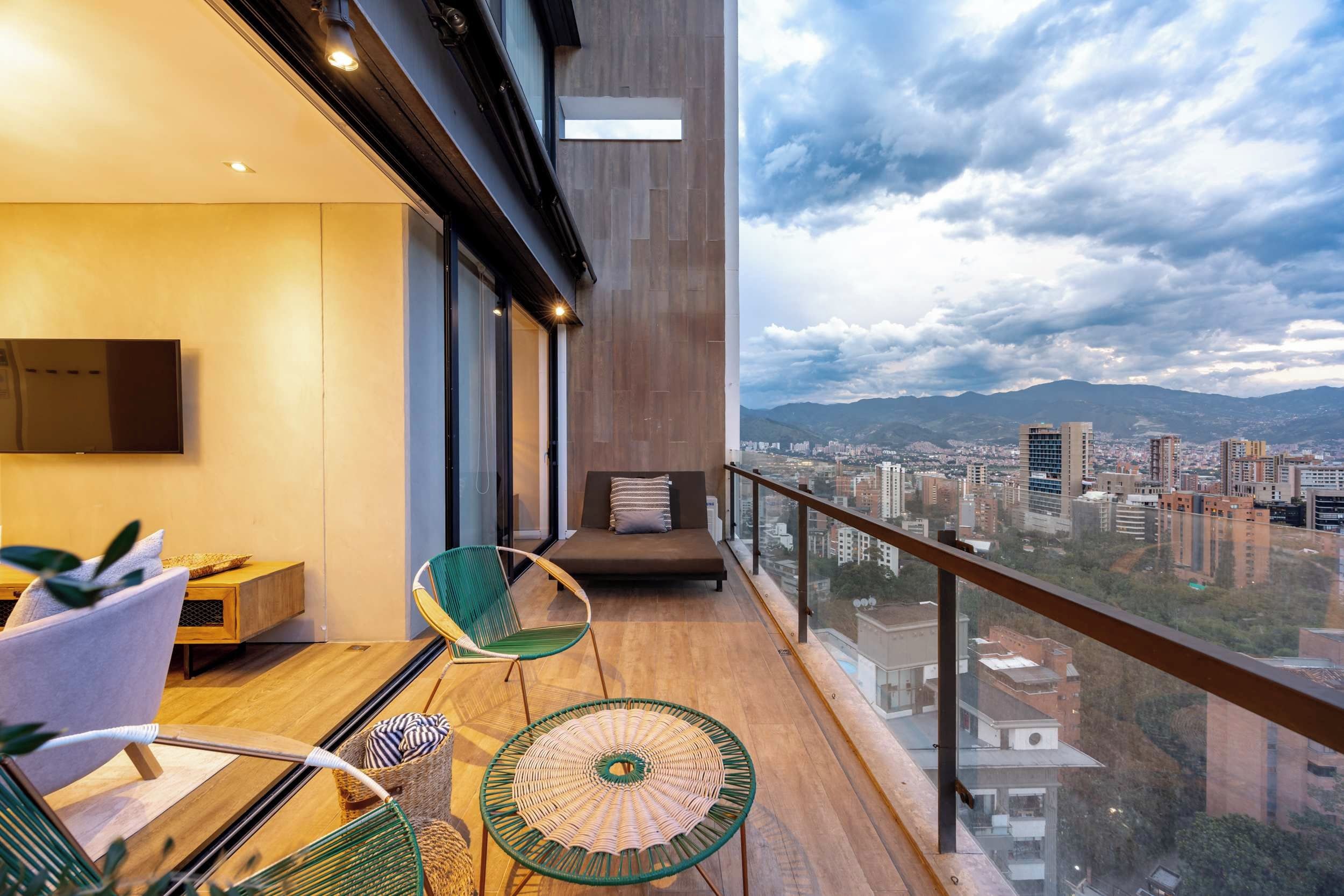 Un balcon moderne avec vue sur la ville, un canapé et deux fauteuils.
