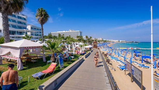 Ein Strandweg mit Liegestühlen, Sonnenschirmen und einem Massagedachzelt.
