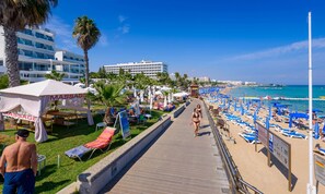 Uma passarela à beira-mar com espreguiçadeiras, guarda-sóis e uma tenda de massagem.