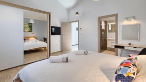 A modern hotel room with a large bed, a desk, a mirror, and a TV.