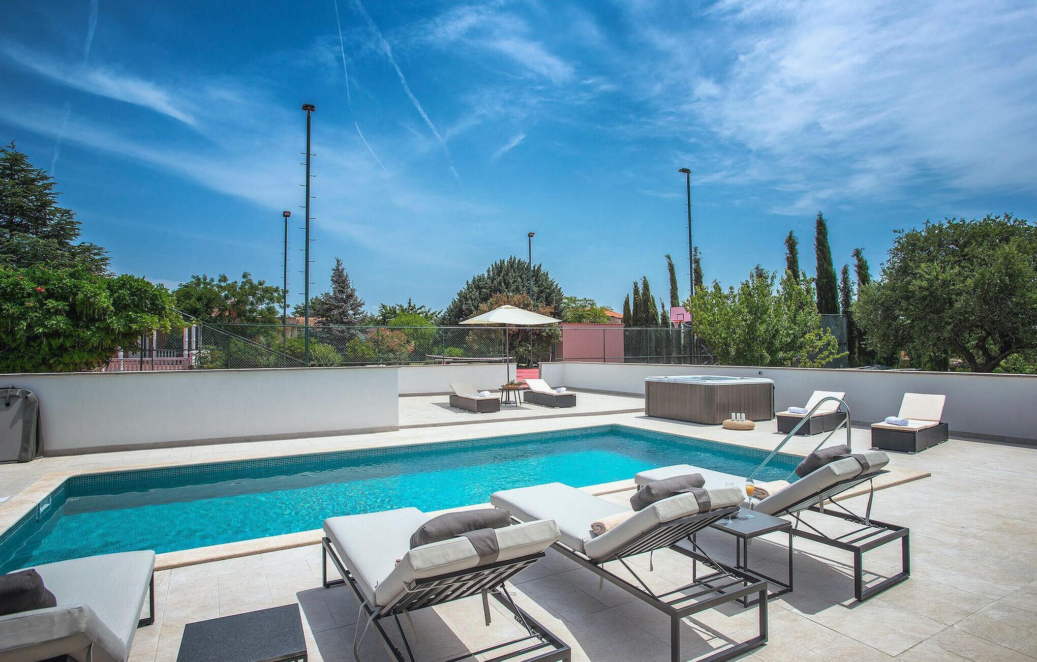 Un espace piscine aménagé sur le toit, avec des chaises longues et un jacuzzi.