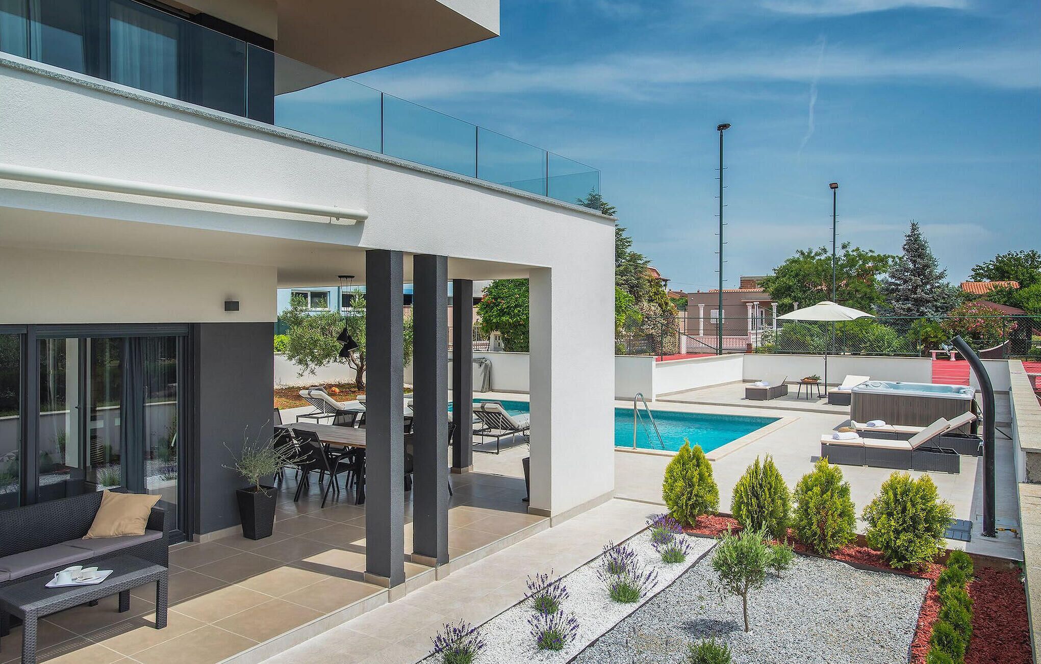 A modern outdoor area with a pool, lounge chairs, and a dining area with a table and chairs.