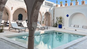 Una piscina al aire libre, sombrillas, sillones reclinables de piscina