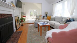 Un salon avec une cheminée, un téléviseur, un canapé, une table basse et une vue sur l’extérieur.