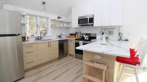 Une cuisine moderne avec des armoires blanches, des appareils en acier inoxydable et un plan de travail en bois.
