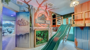 A children's play area themed as Jurassic Park with a slide and a mural.