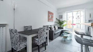 Un salon moderne comprenant un coin repas, un canapé, une table basse en verre et un bar.