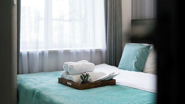 A hotel room with a bed, a tray with rolled towels, a small potted plant, and sheer curtains. - Stay Inn on Lusavorich 3 (Yerevan)