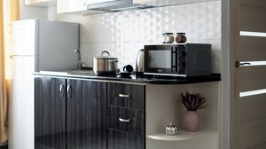 A modern kitchen with a refrigerator, microwave, and stove. There is a potted plant and a small decorative item on the counter. - Stay Inn on Lusavorich 3 (Yerevan)