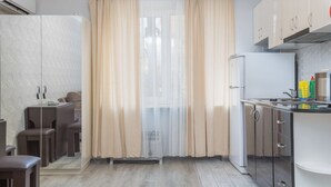 A compact kitchen with a dining area, featuring a modern design with beige curtains, a built-in stove, and a small dining table with chairs. - Stay Inn on Lusavorich 3 (Yerevan)