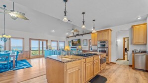 A spacious kitchen with wooden cabinets, a large island, and a view of the sea. - Soundfront Dog Friendly w/ Hot Tub, Elevator, Private Sound Access, Media Room (Buxton)