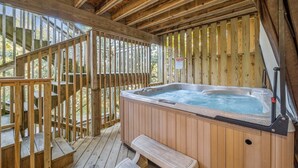 A wooden deck with a hot tub and a bench. - Soundfront Dog Friendly w/ Hot Tub, Elevator, Private Sound Access, Media Room (Buxton)