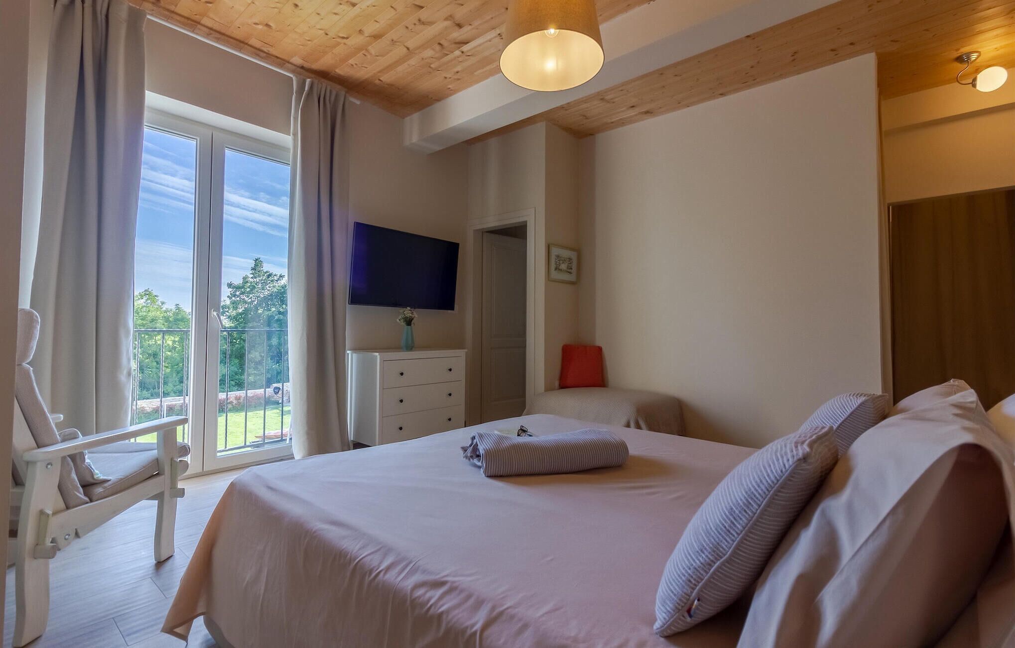 A bedroom with a bed, a TV, a desk, and a chair.