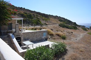 A stone building with outdoor seating and a view of the coastline.