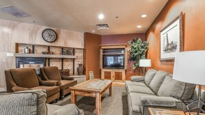 Un salon chaleureux avec une cheminée, un téléviseur et des fauteuils confortables.