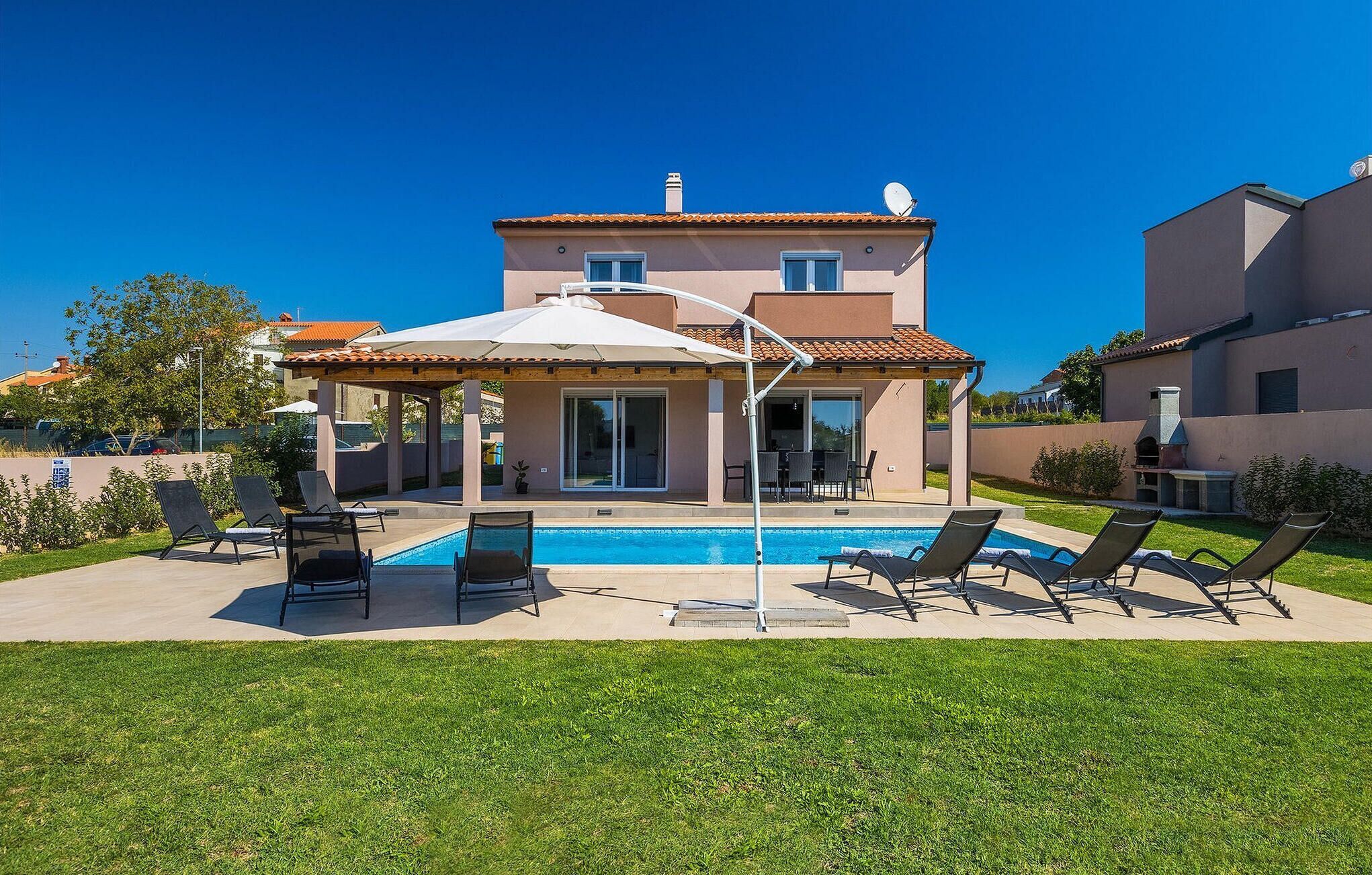 Una casa de dues plantes amb piscina, mobiliari d'exterior i un porxo cobert.