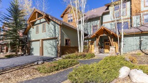 A two-story wooden house with a garage, surrounded by trees and a stone pathway. - 1849 The Seasons 3 Bedroom Townhouse by RedAwning (Keystone)