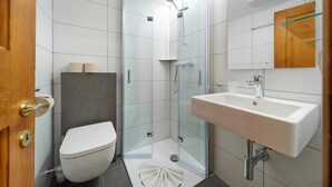 A modern bathroom with a glass-enclosed shower, a white sink, and a toilet. - 5003 Alice im Alpenhaus Montafon (Gargellen)