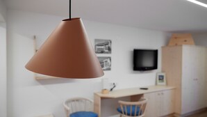 A modern room with a hanging pendant light, a desk, two chairs, and a television on the wall. - 5003 Alice im Alpenhaus Montafon (Gargellen)