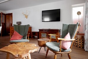Relax in comfort with a flat-screen TV, two armchairs, and a wooden coffee table.