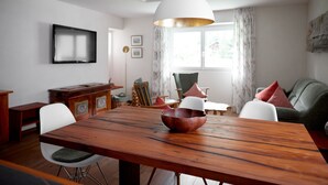 Comedor con mesa de madera, sillas blancas y una lámpara colgante grande de color blanco.