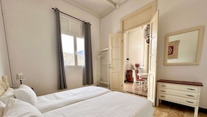 Une chambre d’hôtel avec un grand lit, un bureau avec des tiroirs, une chaise, une lampe et une armoire.