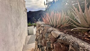 Un mur de pierre, un jardin de cactus et une montagne en arrière-plan.