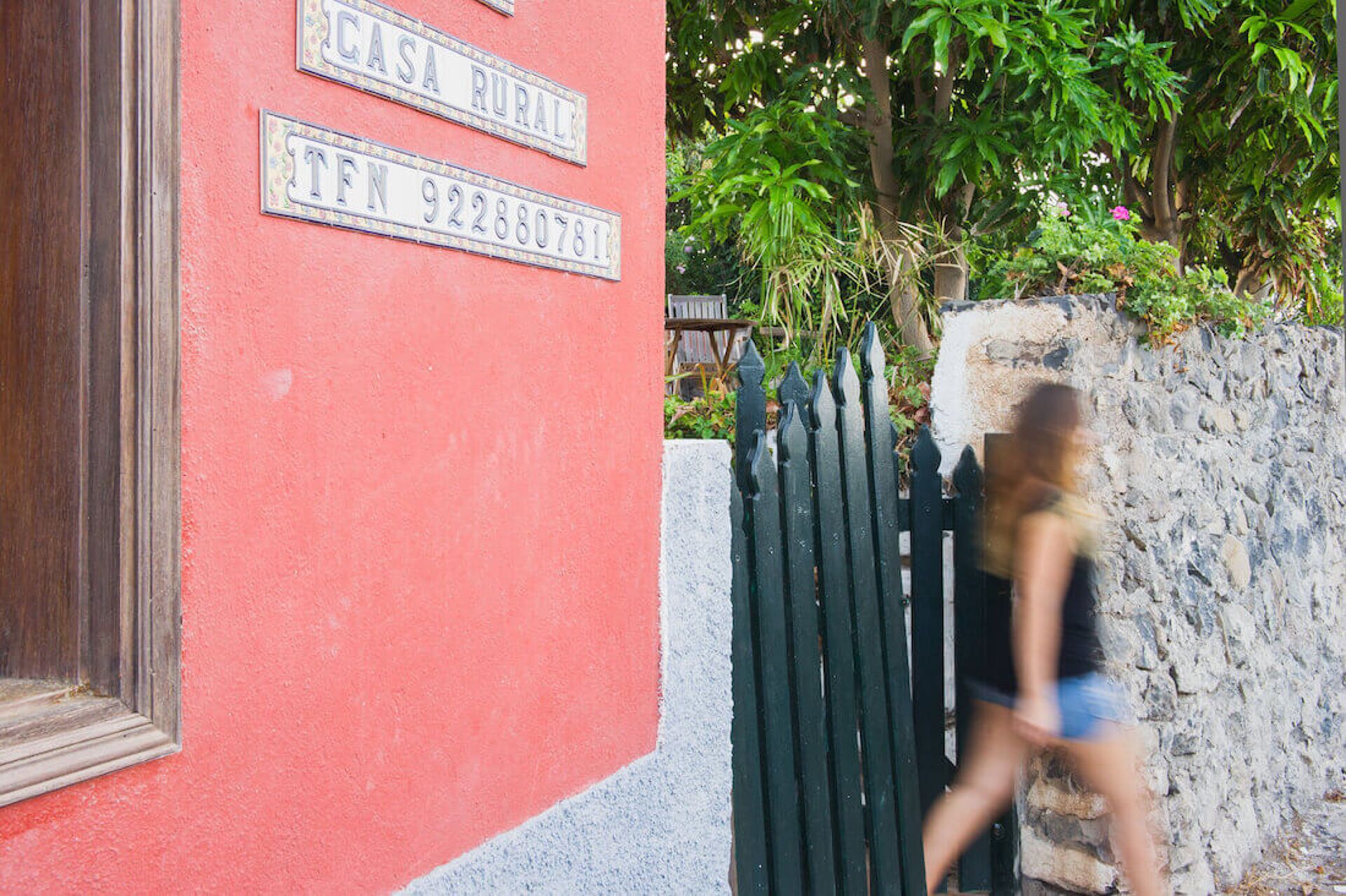 A red building with a black gate and a stone wall.